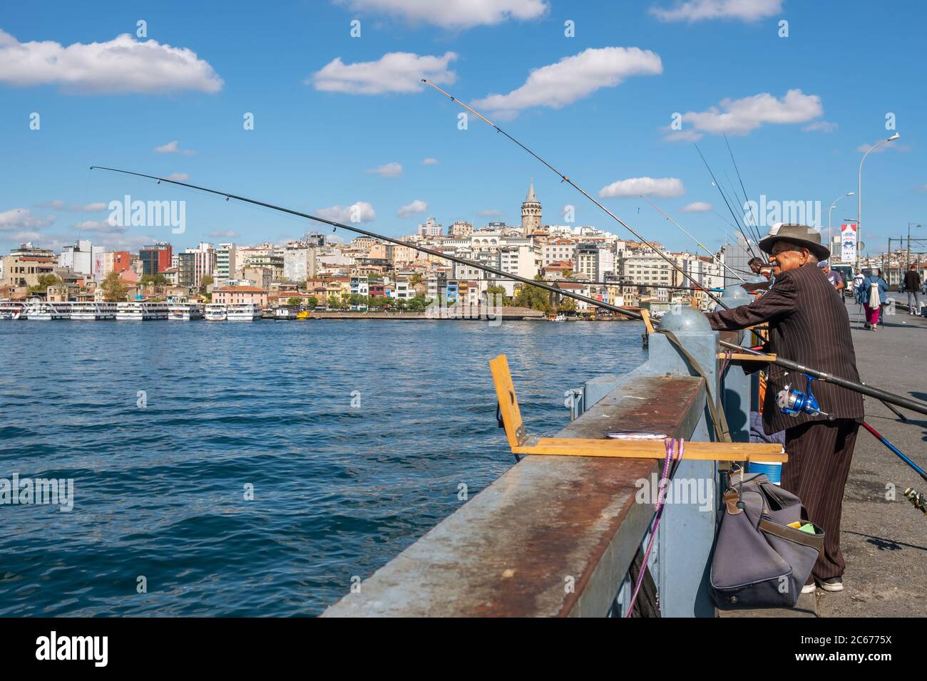 Pescatore turco non identificato sul ponte di Galata con la torre di Galata sullo sfondo a Istanbul Foto Stock