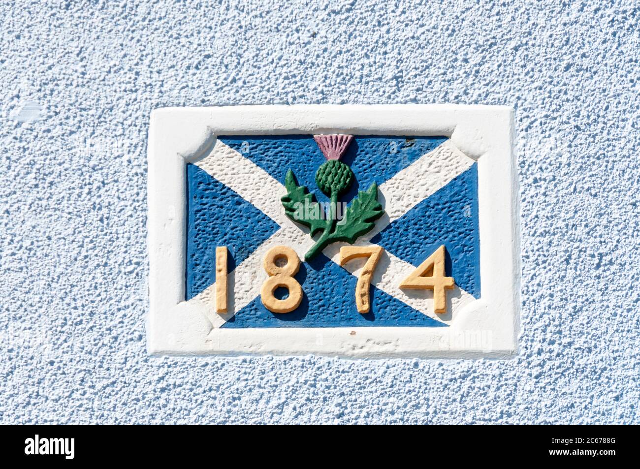 Bandiera scozzese, il salstire, e il simbolo del fischio su una targa a 1874 date nel muro di Thistle House, Pittenweem nel Neuk orientale di Fife. Foto Stock
