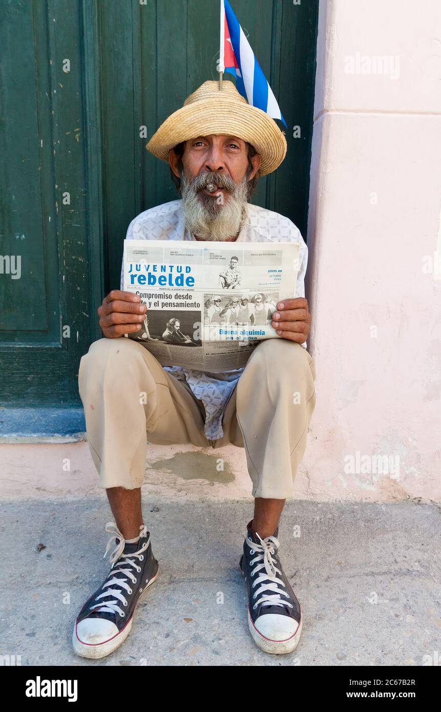 Vecchio a l'Avana con un giornale e fumando un sigaro cubano Foto Stock