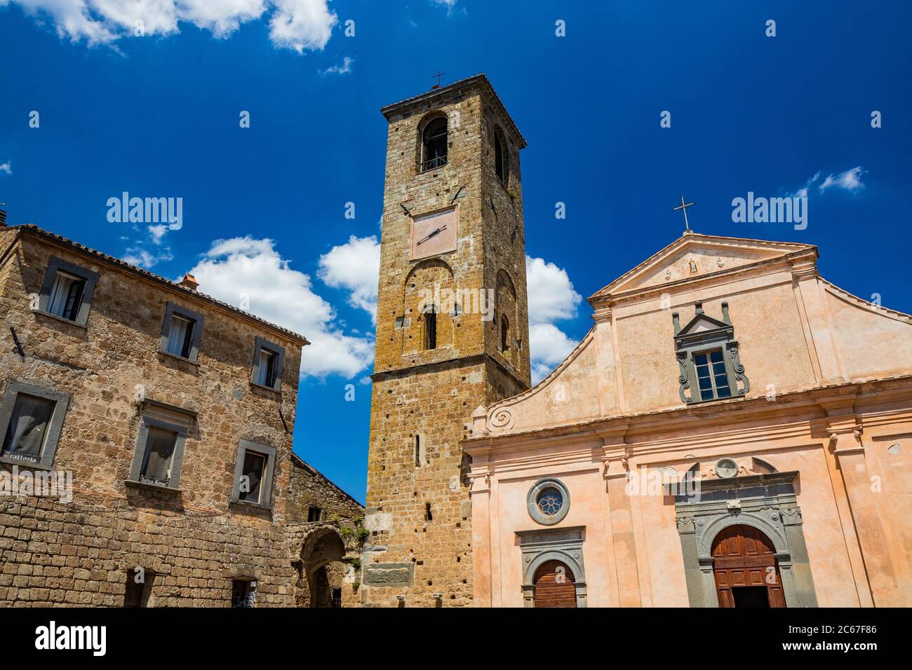 Civita di Bagnoregio, Viterbo, Tuscia, Lazio, Italy. La Chiesa di San Donato con il campanile e l'orologio. Tre porte in legno. Foto Stock