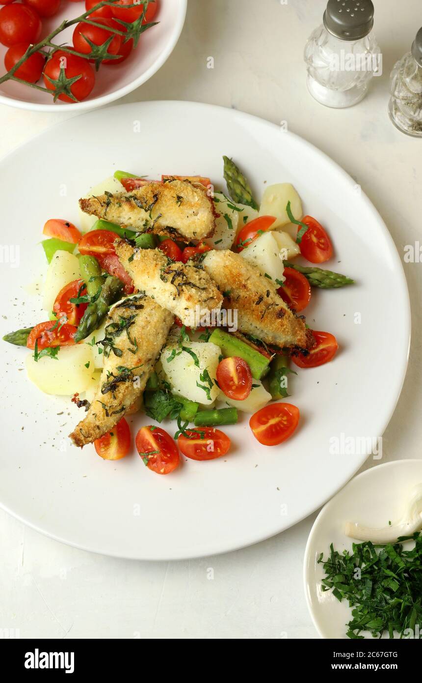 Concetto di cibo sano. Insalata fresca con filetti di pesce gurnard rosso gratin, pomodori ciliegini di asparagi, patate ed erbe. Vista dall'alto. Foto Stock