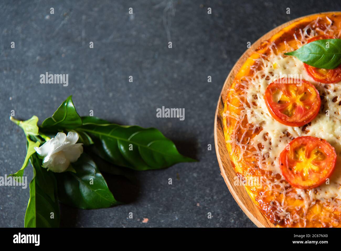 Pizza con una vista e una prospettiva diversa con un fiore e foglie come decorazioni e l'uso di fuoco selettivo. Foto Stock
