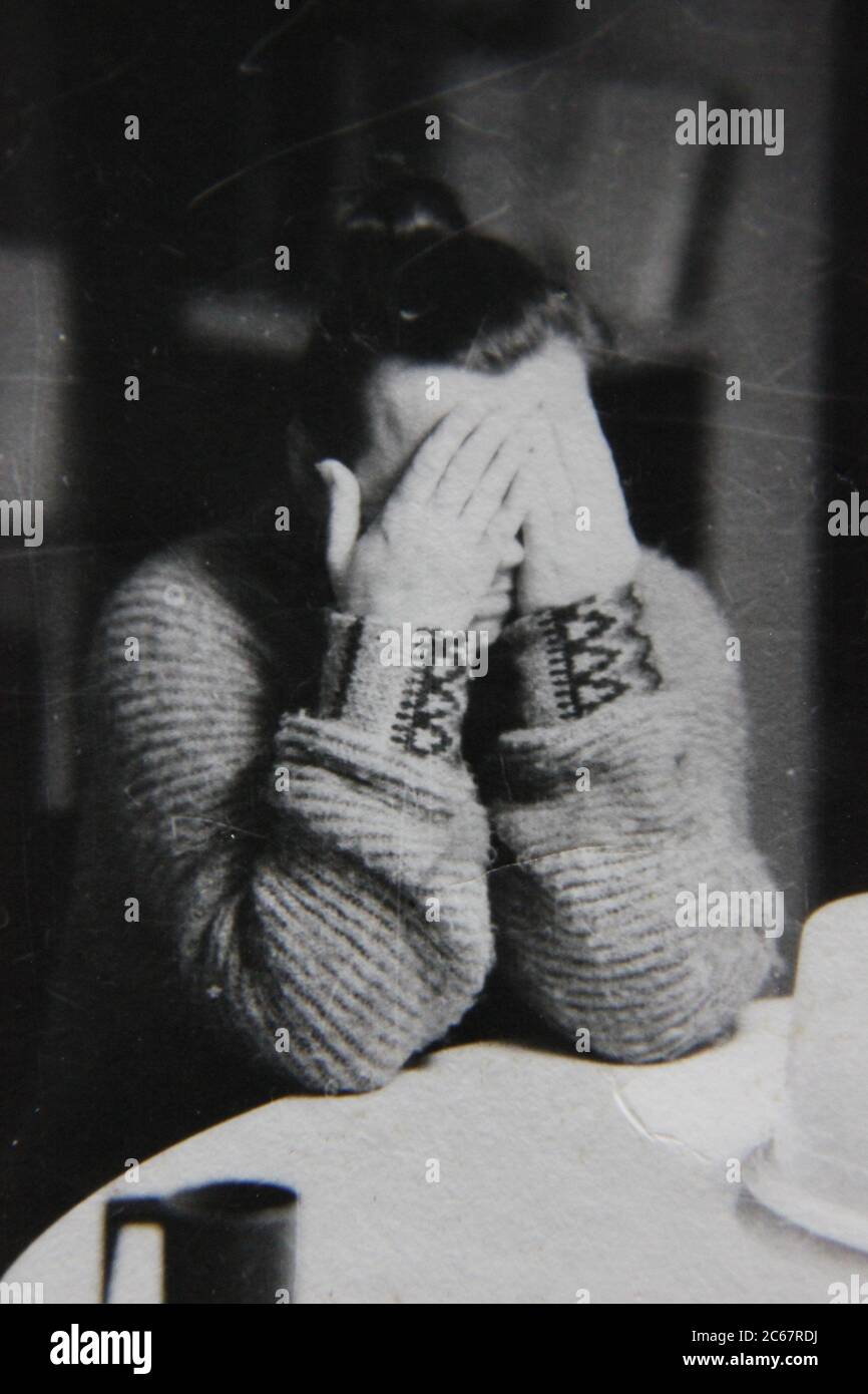 Fine anni '70 vintage nero e bianco stile di vita fotografia di una donna dell'Europa orientale nascondendo il suo volto. Foto Stock