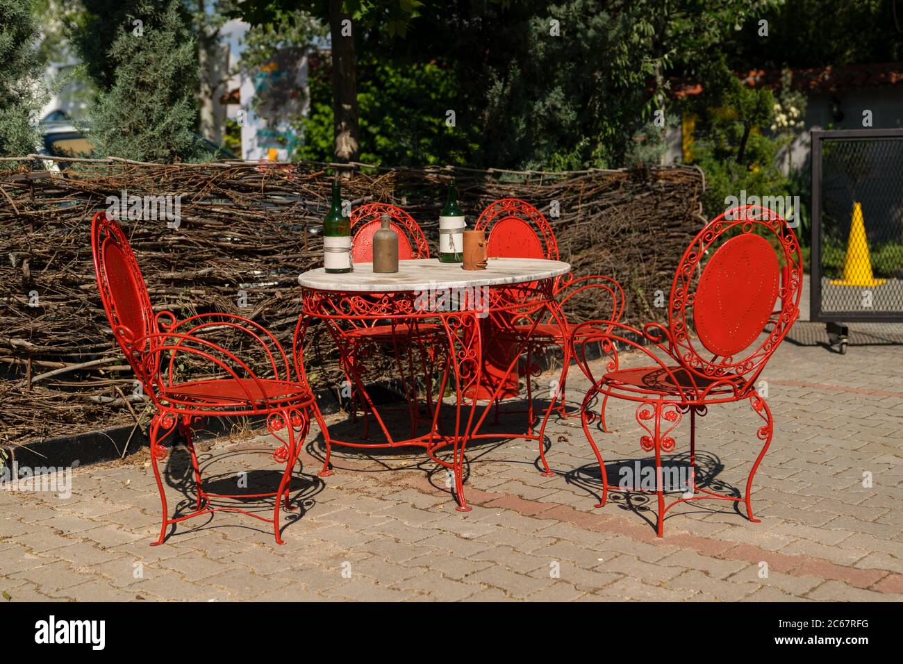 Vecchi mobili in ferro battuto rosso antico, esterno shabby chic. Set di  tavolo rotondo con bottiglia di vino e tazze e sedie in giardino. Tavolo  sul caffè bac Foto stock - Alamy