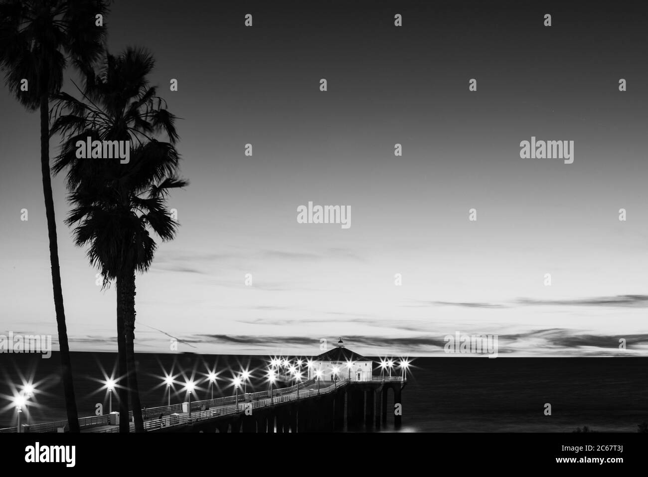 Le palme si stagliano contro il cielo limpido e il molo di Manhattan Beach, California, USA Foto Stock