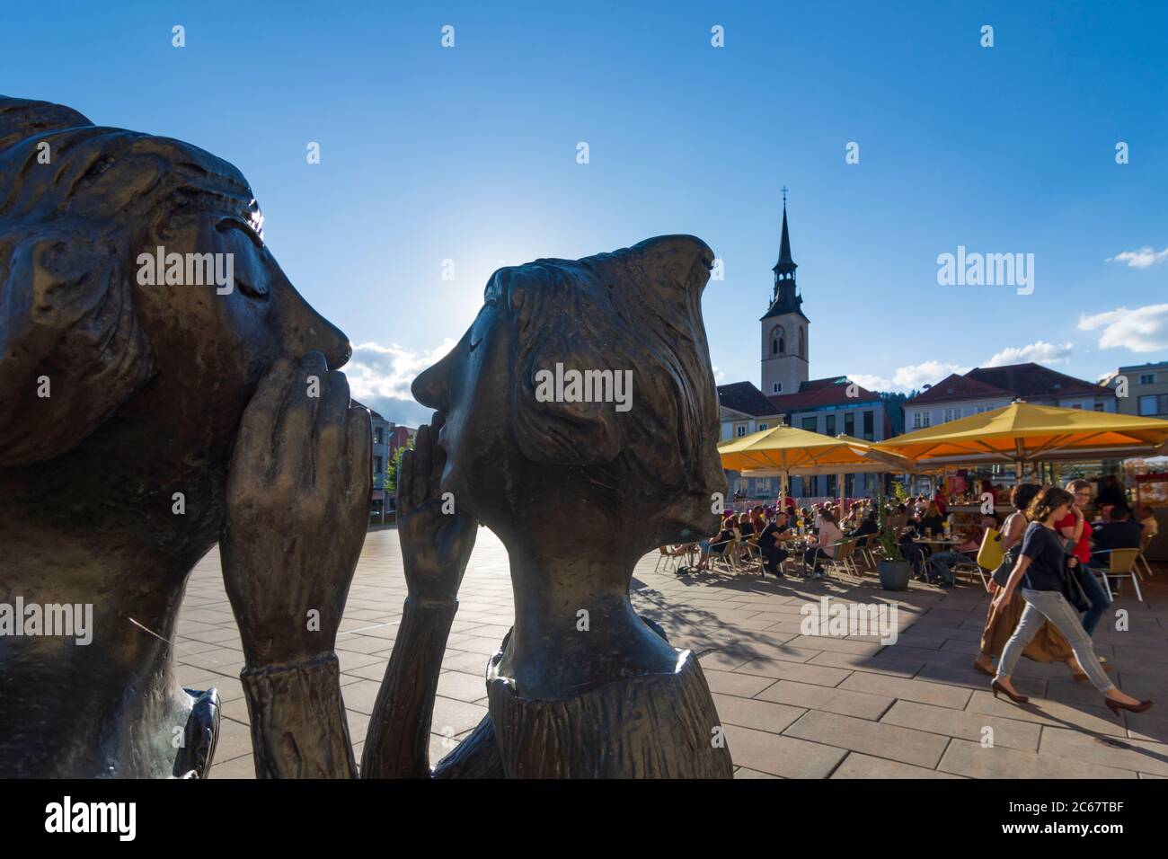 Bruck an der Mur: Piazza principale Koloman-Wallisch-Platz, sculture 'tadtgespräch' due donne che parlano l'una con l'altra, chiesa parrocchiale a Murau-Murtal, Steie Foto Stock