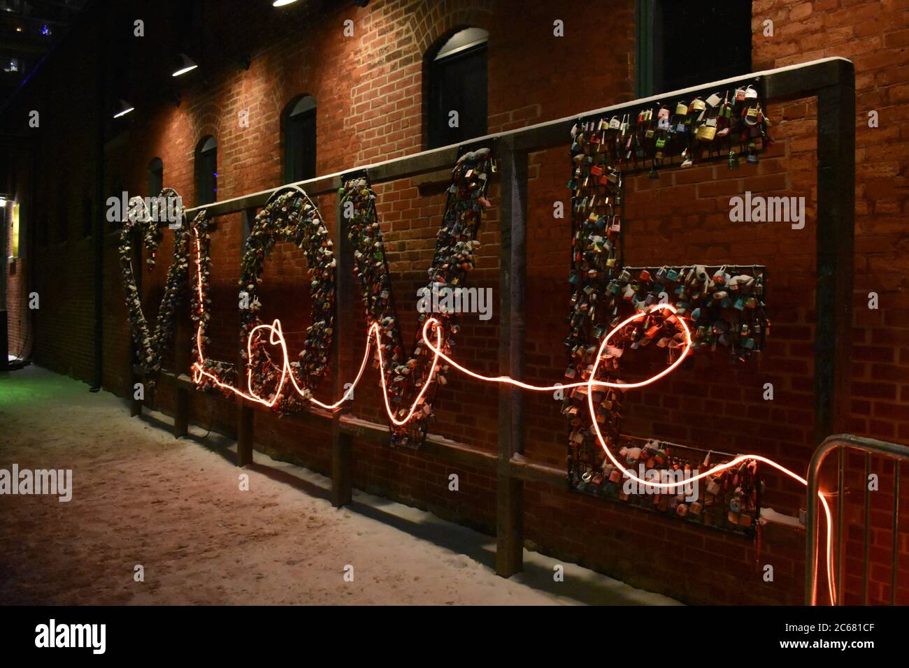 Amore scritto in lucchetti e una luce al neon sopra la parte superiore. Insegna d'amore di notte in inverno nello storico quartiere della distilleria di Toronto. Foto Stock