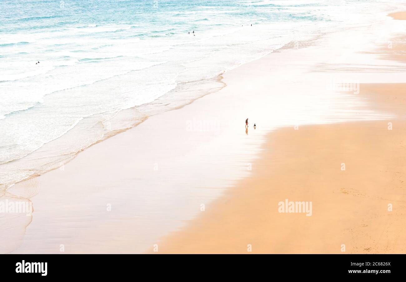 Lone Man cammina un cane sulla spiaggia - Perranporth, Cornovaglia, Regno Unito Foto Stock