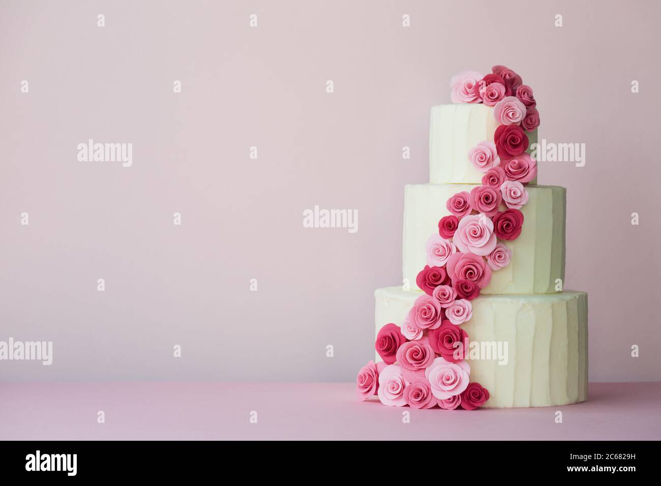 Torta nuziale a più livelli con rose in pasta di zucchero in rosa Foto Stock