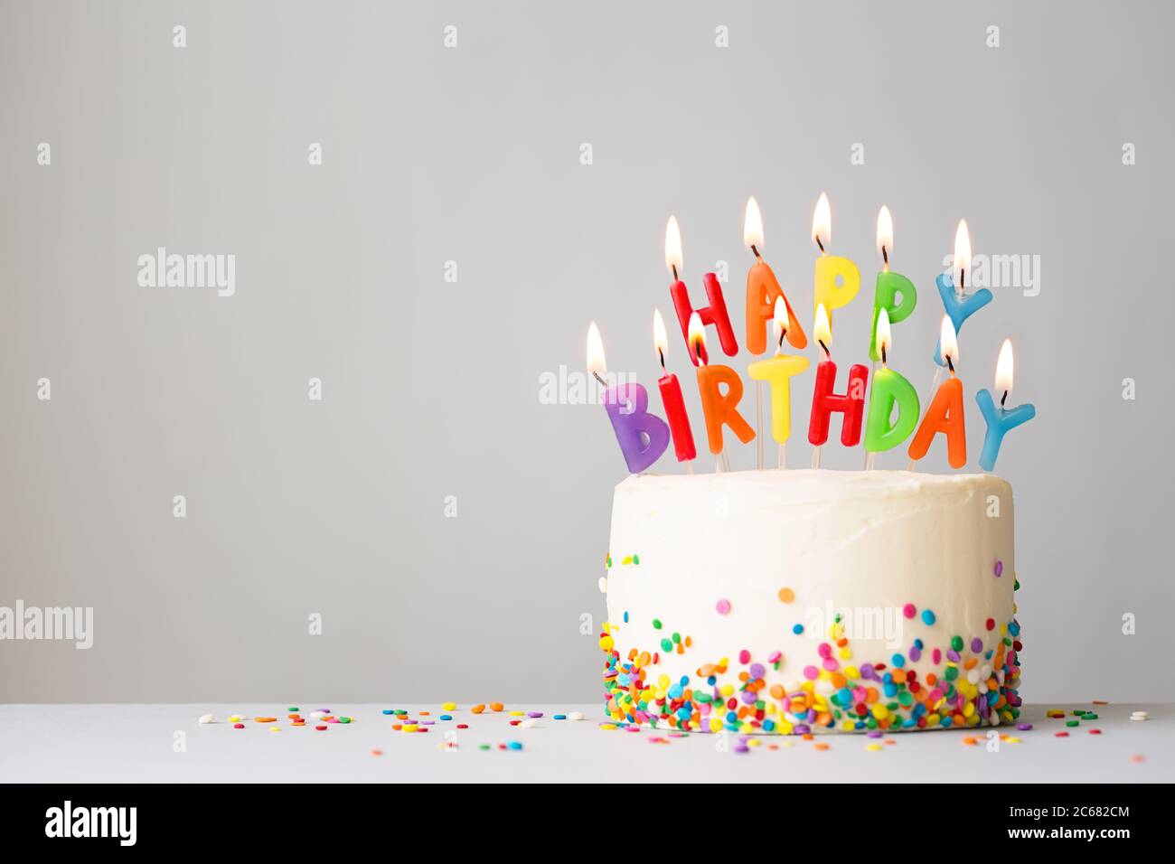 Torta di compleanno con candele colorate che ortografia buon compleanno Foto Stock