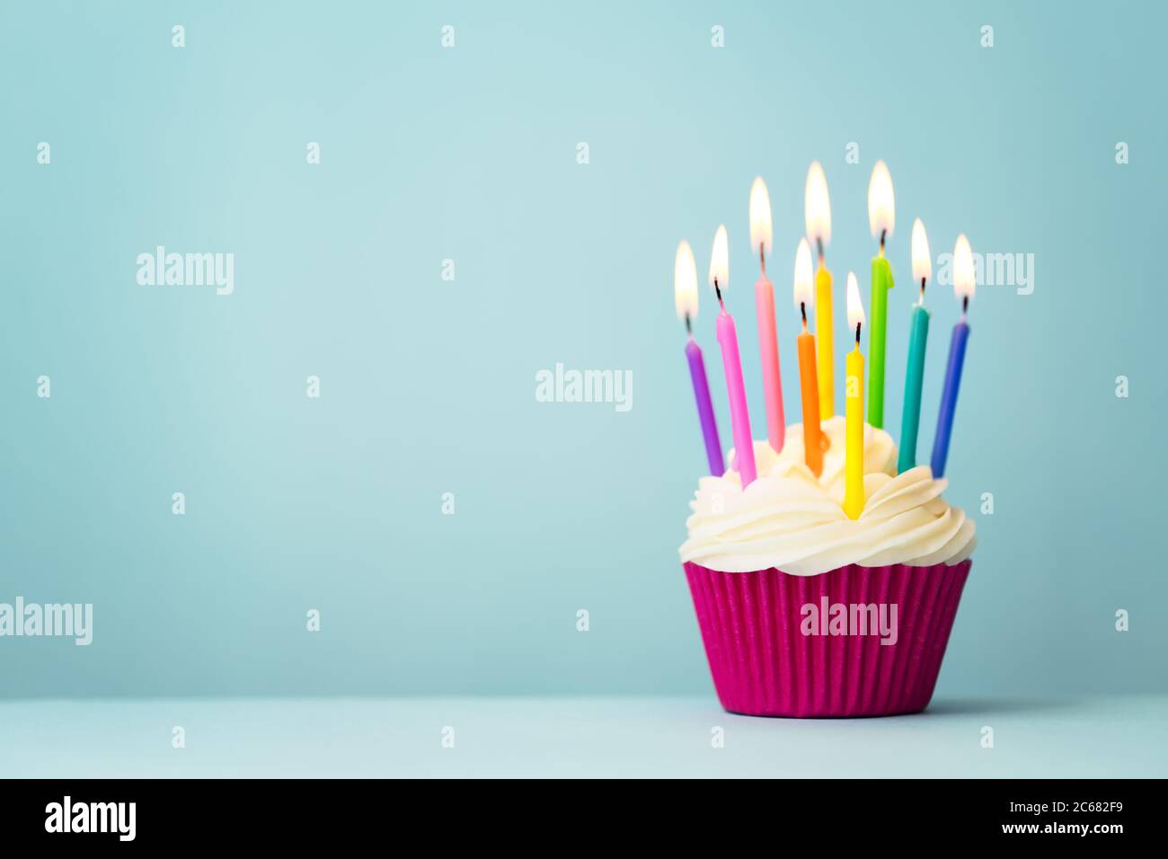Cupcake di compleanno con candele arcobaleno Foto Stock