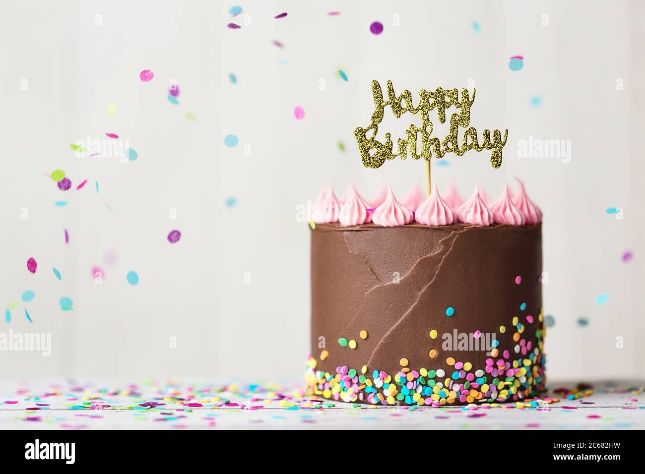 Torta di compleanno al cioccolato con buon banner di compleanno e confetti in caduta Foto Stock