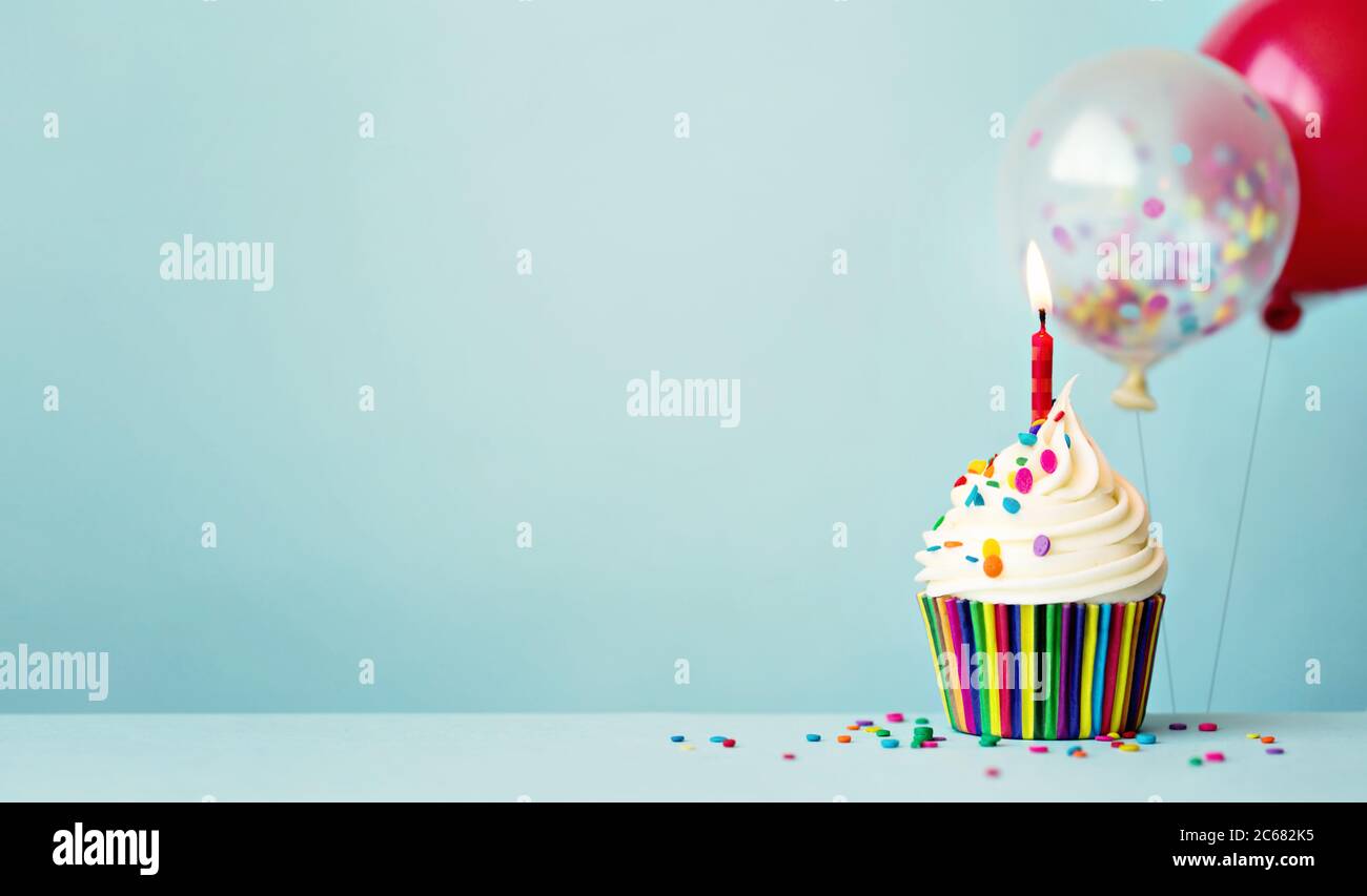 Cupcake di compleanno con palloncini colorati e confetti Foto Stock