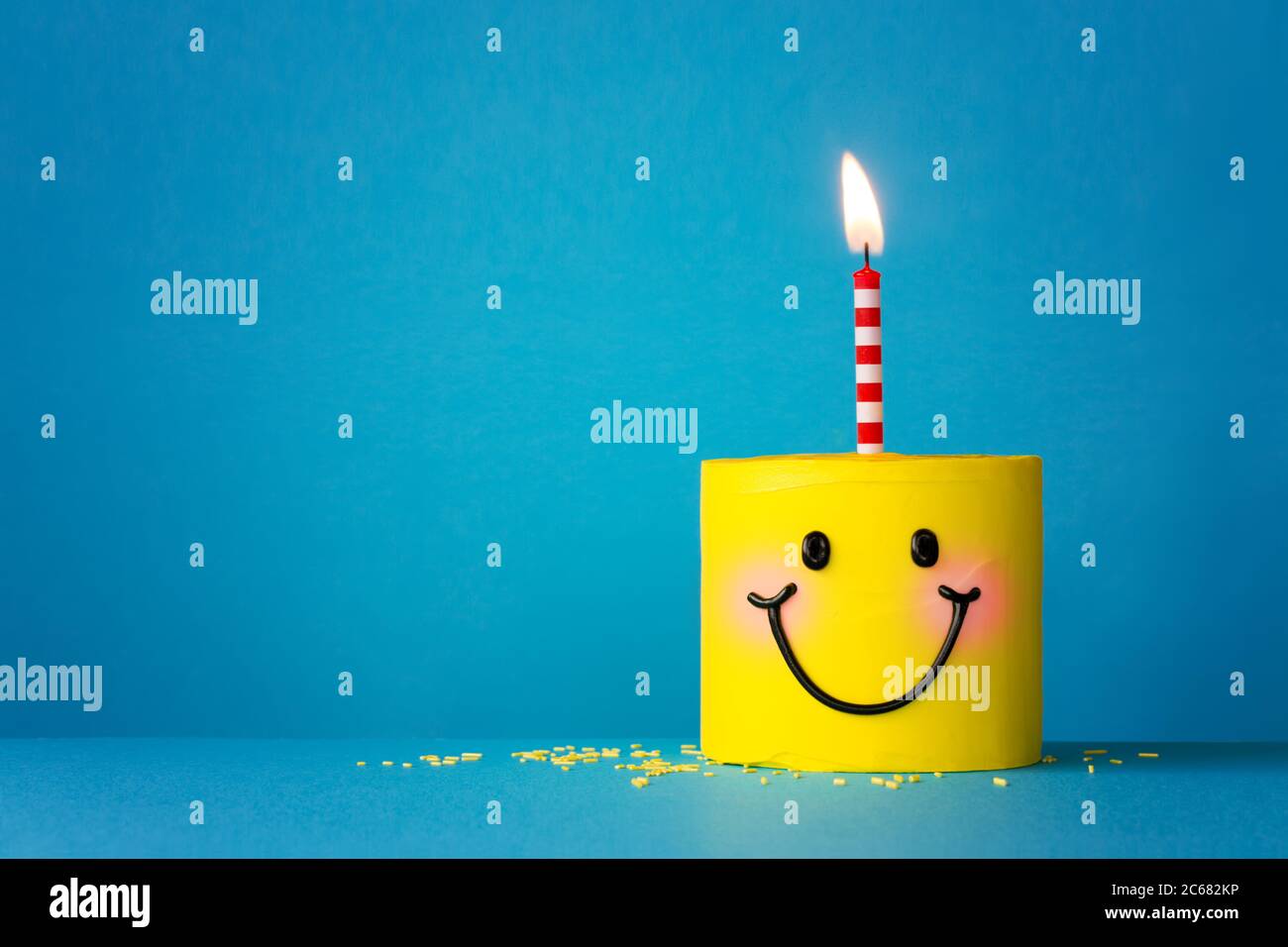 Torta di compleanno di faccia di sorriso gialla con una candela Foto Stock