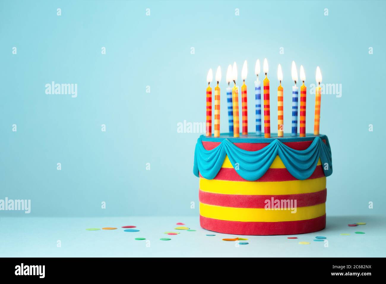 Torta di compleanno dai colori vivaci con candele colorate Foto Stock