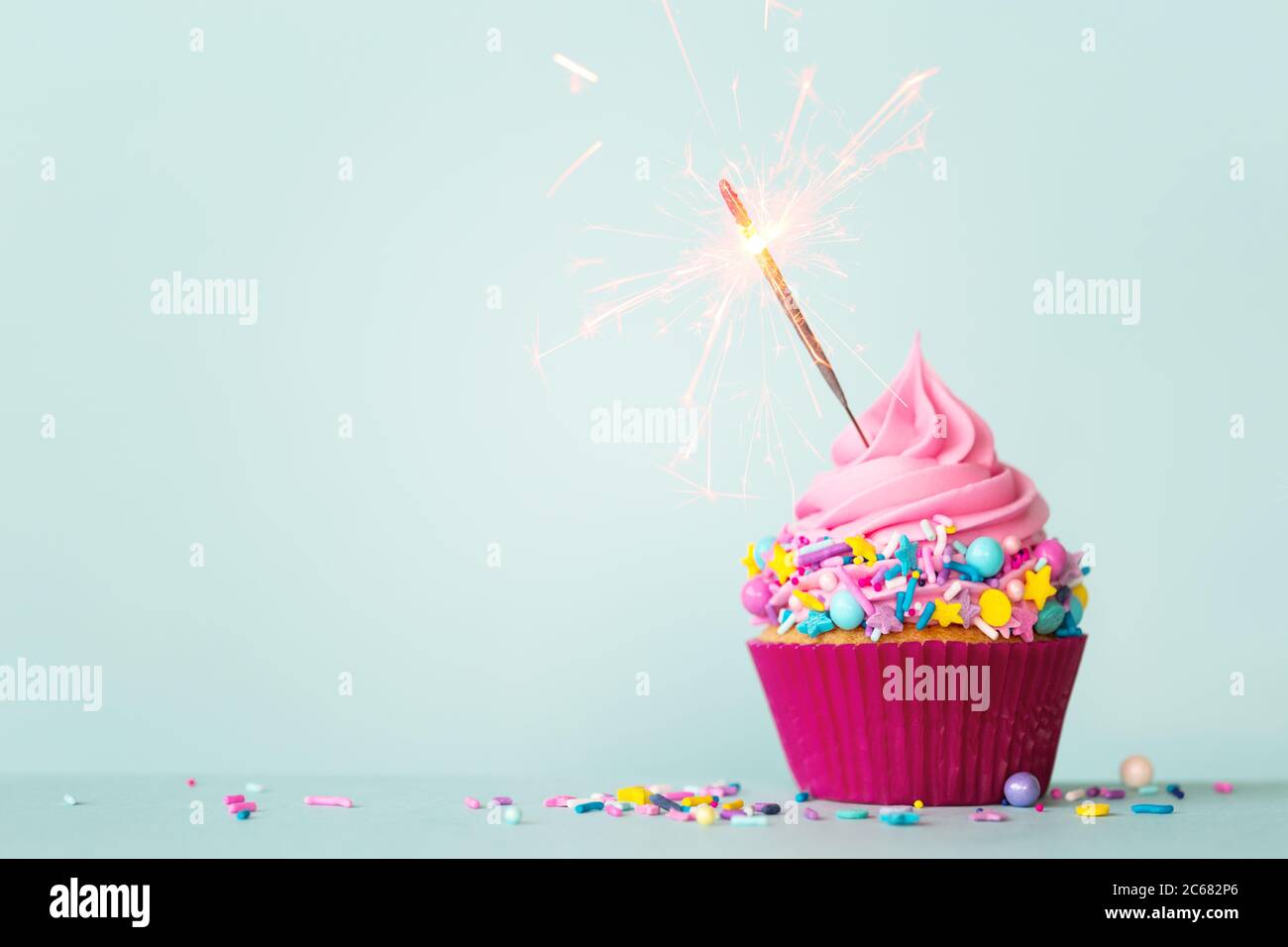 Cupcake di compleanno con sparkler e spruzzi colorati Foto Stock
