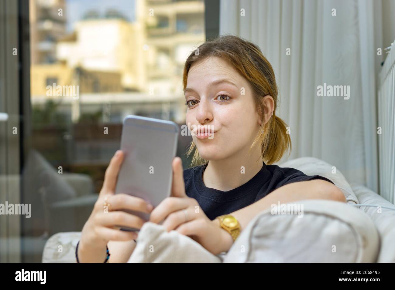 Ragazza adolescente che prende un selfie con anatra faccia a casa Foto Stock
