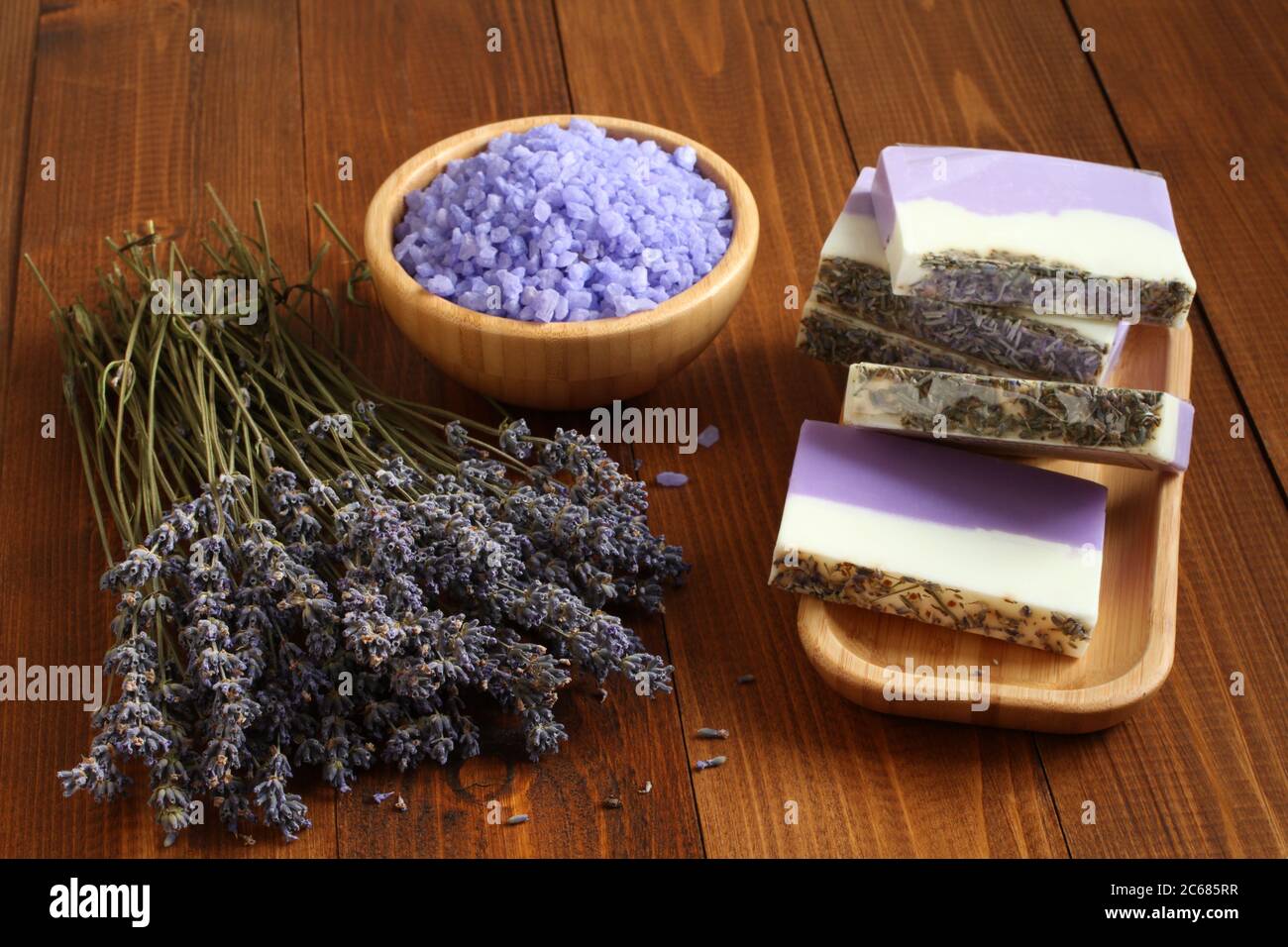 Sale marino con lavanda in una ciotola di bambù, sapone fatto da lavanda, olio d'oliva e burro di cacao su una piastra di bambù e fiori di lavanda essiccati si trovano Foto Stock