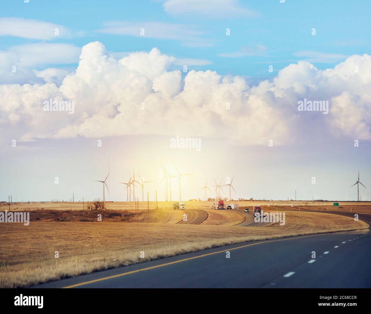 Il traffico si sposta lungo un'autostrada interstatale con turbine eoliche al tramonto Foto Stock