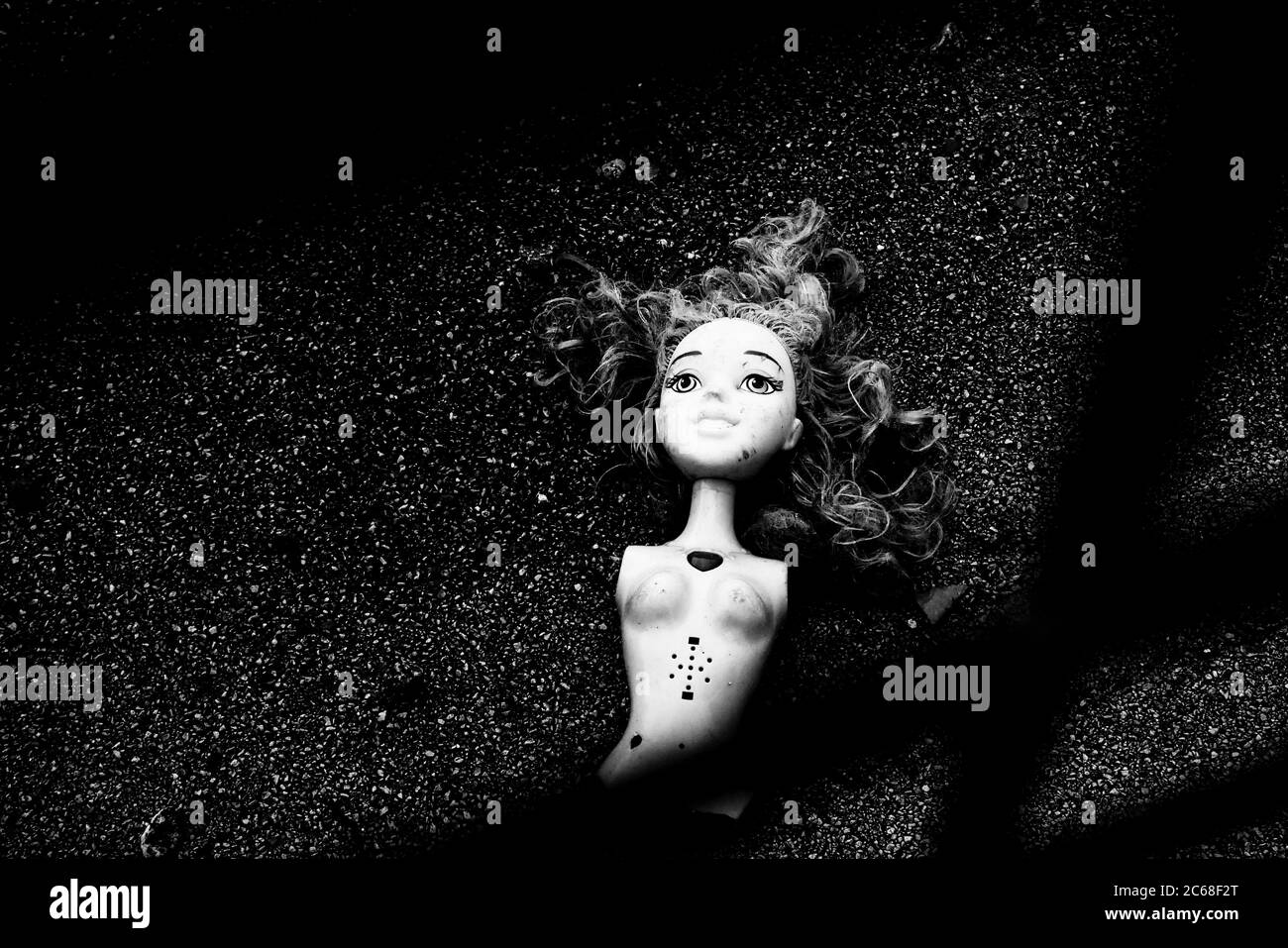 Bambola creepy, rotta scartata sul marciapiede, strappata, arti mancanti, nessuna braccia, nessuna gamba, gettata fuori, sulla strada, infanzia persa, giocattolo perso Foto Stock
