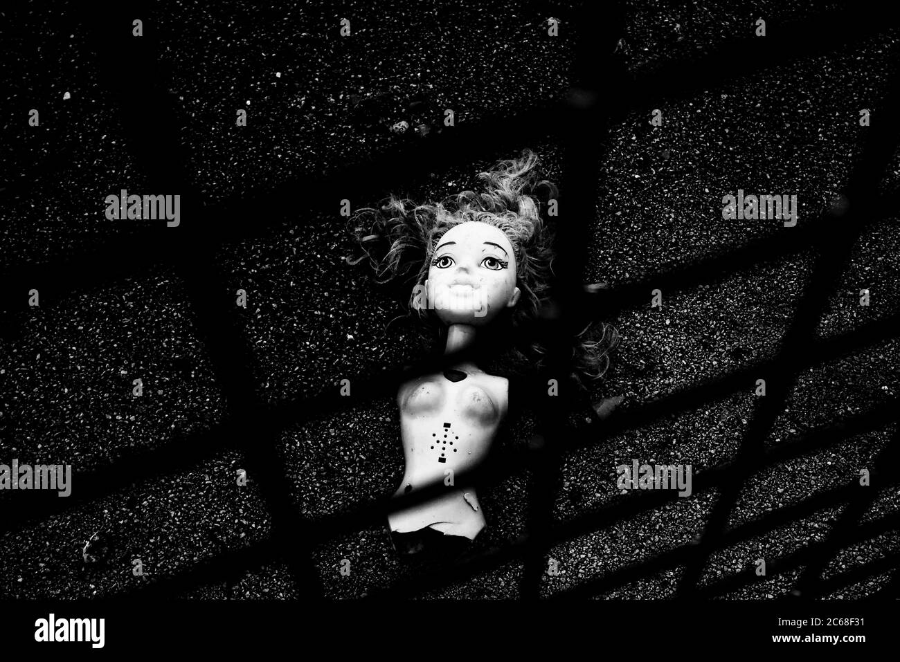 Bambola creepy, rotta scartata sul marciapiede, strappata, arti mancanti, nessuna braccia, nessuna gamba, gettata fuori, sulla strada, infanzia persa, giocattolo perso Foto Stock