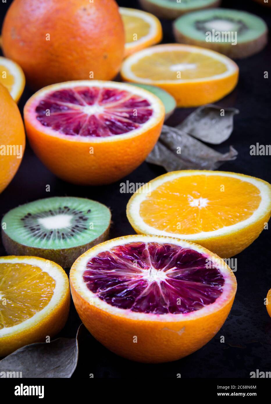 Alcune sezioni di arance, arance di sangue, kiwi su sfondo nero. Foto Stock