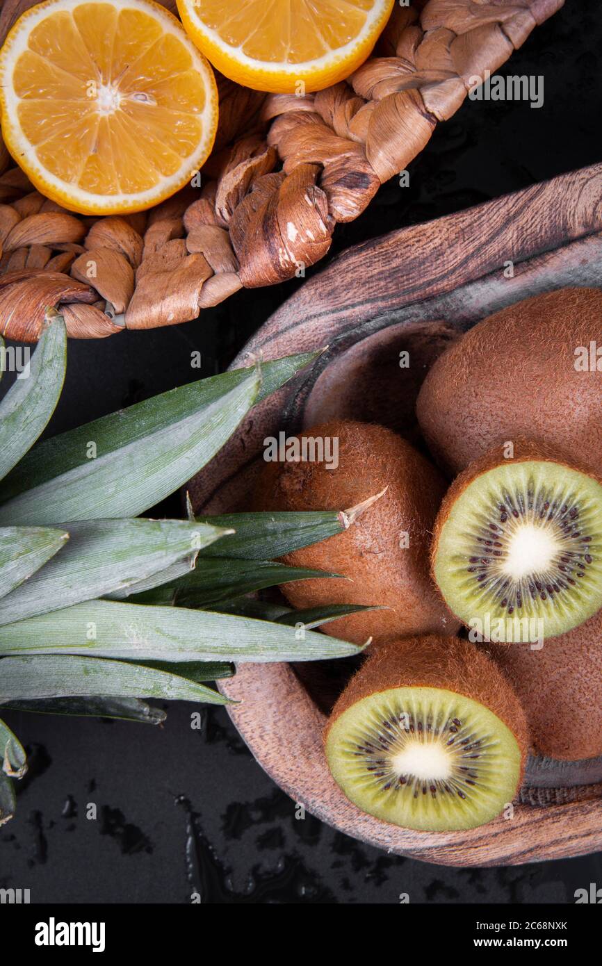 Arance dolci tritate, kiwis dimezzati e ananas su fondo nero. Foto Stock