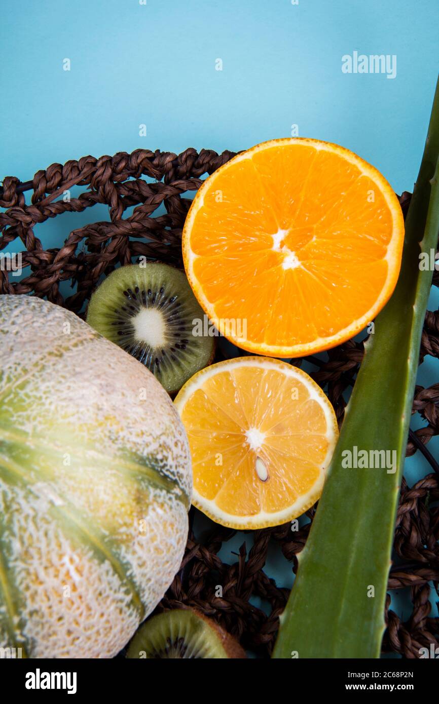 Kiwifruits, metà arancio, melone di melone di melone e foglia di aloe vera in cesto di tessuto. Foto Stock