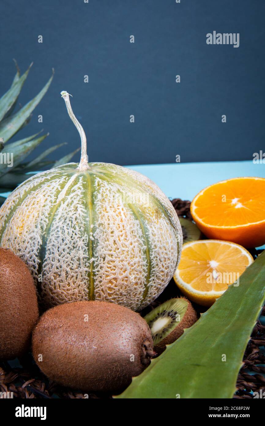 Kiwifruits, metà arancio, melone di melone di melone e foglia di aloe vera in cesto di tessuto. Foto Stock