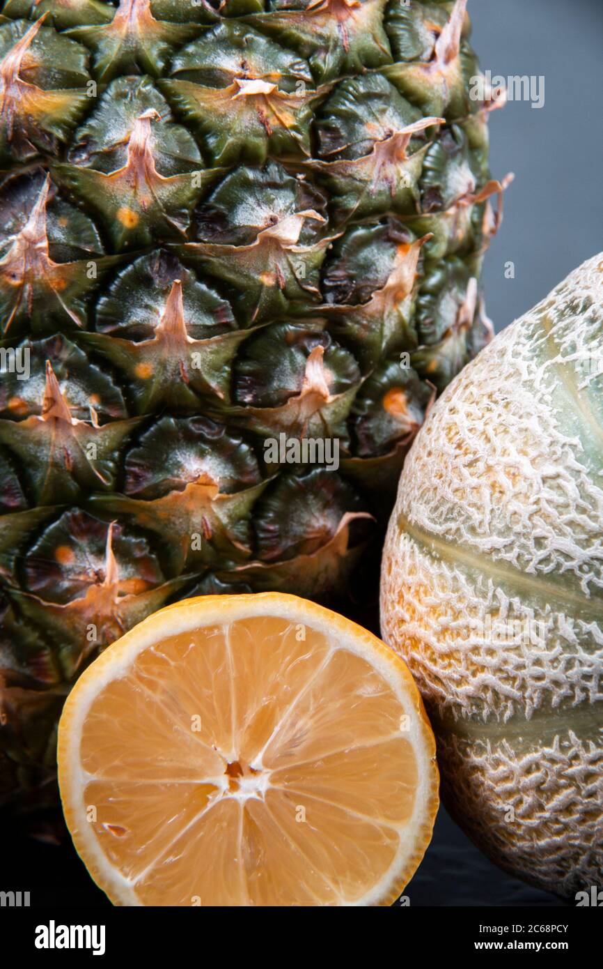 Un colpo vicino di una rugiada in luna di miele, un ananas fresco e una sezione trasversale di un arancio. Foto Stock