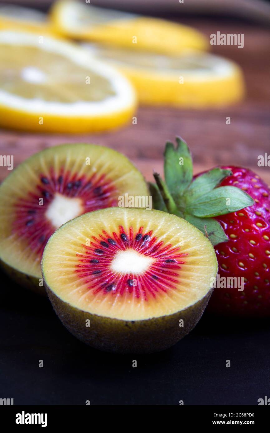 Vista ravvicinata di minuscoli frutti, kiwi verdi e rossi e una fragola matura rossa. Foto Stock