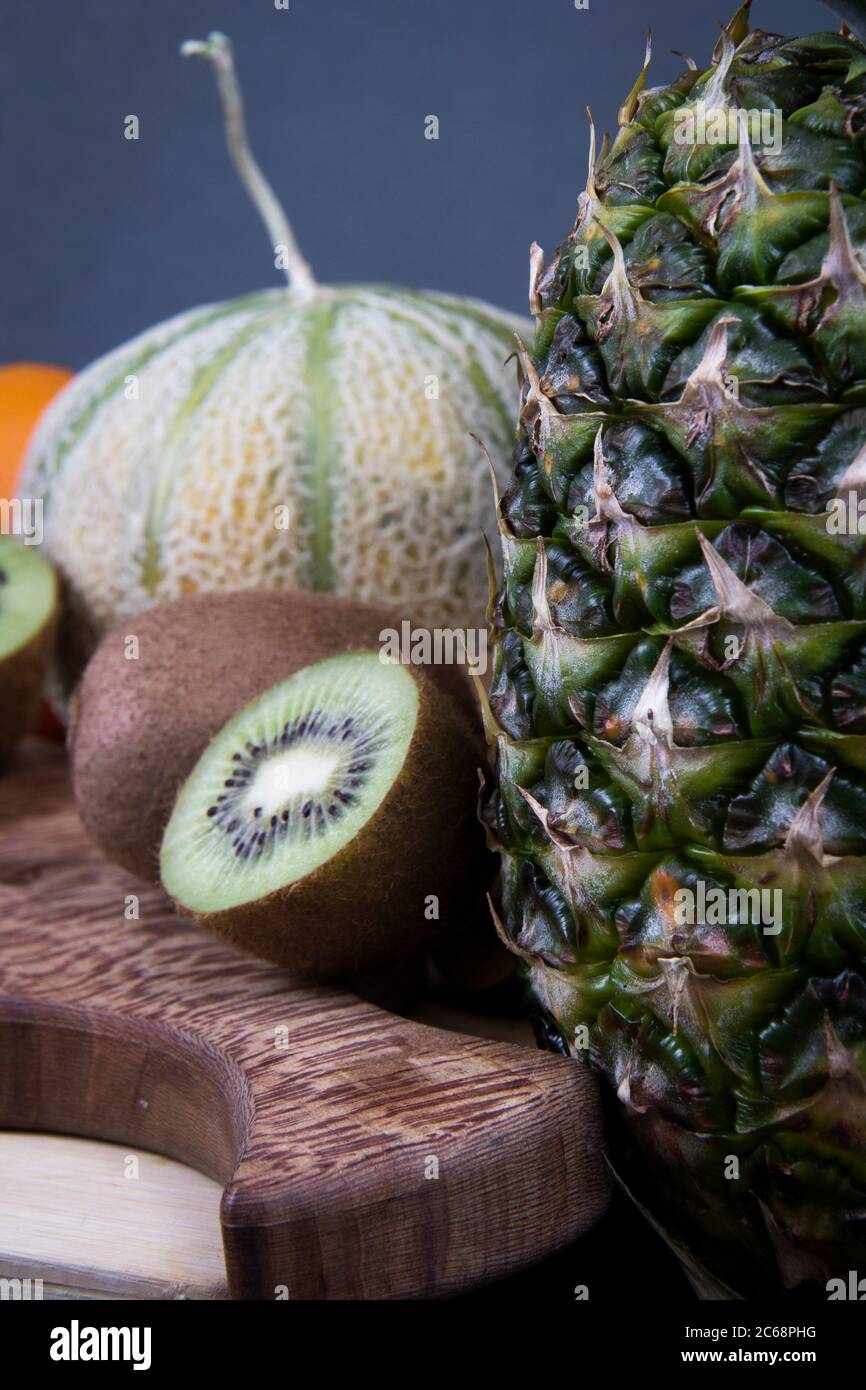 Un colpo vicino di alcuni frutti include un grande ananas, melone di miele e kiwis. Foto Stock
