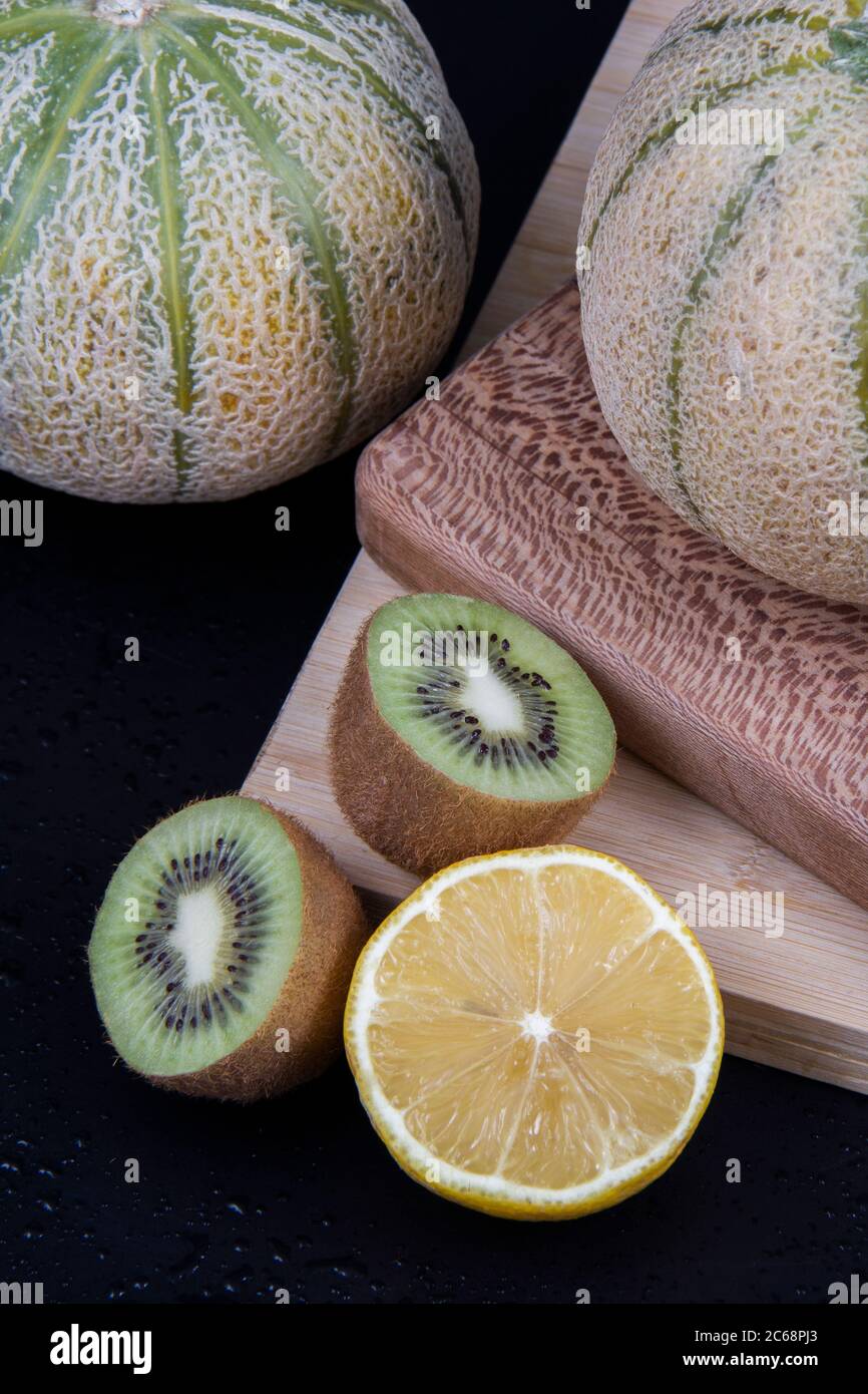 Meloni di melone, un mezzo limone, kiwi tritati verdi e gialli in una cornice. Foto Stock