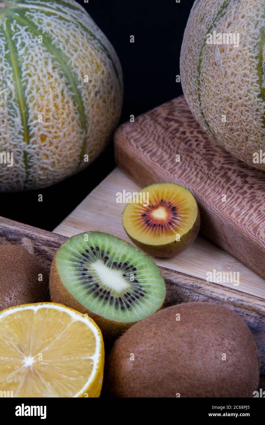 Meloni di melone, un mezzo limone, kiwi tritati verdi e gialli in una cornice. Foto Stock