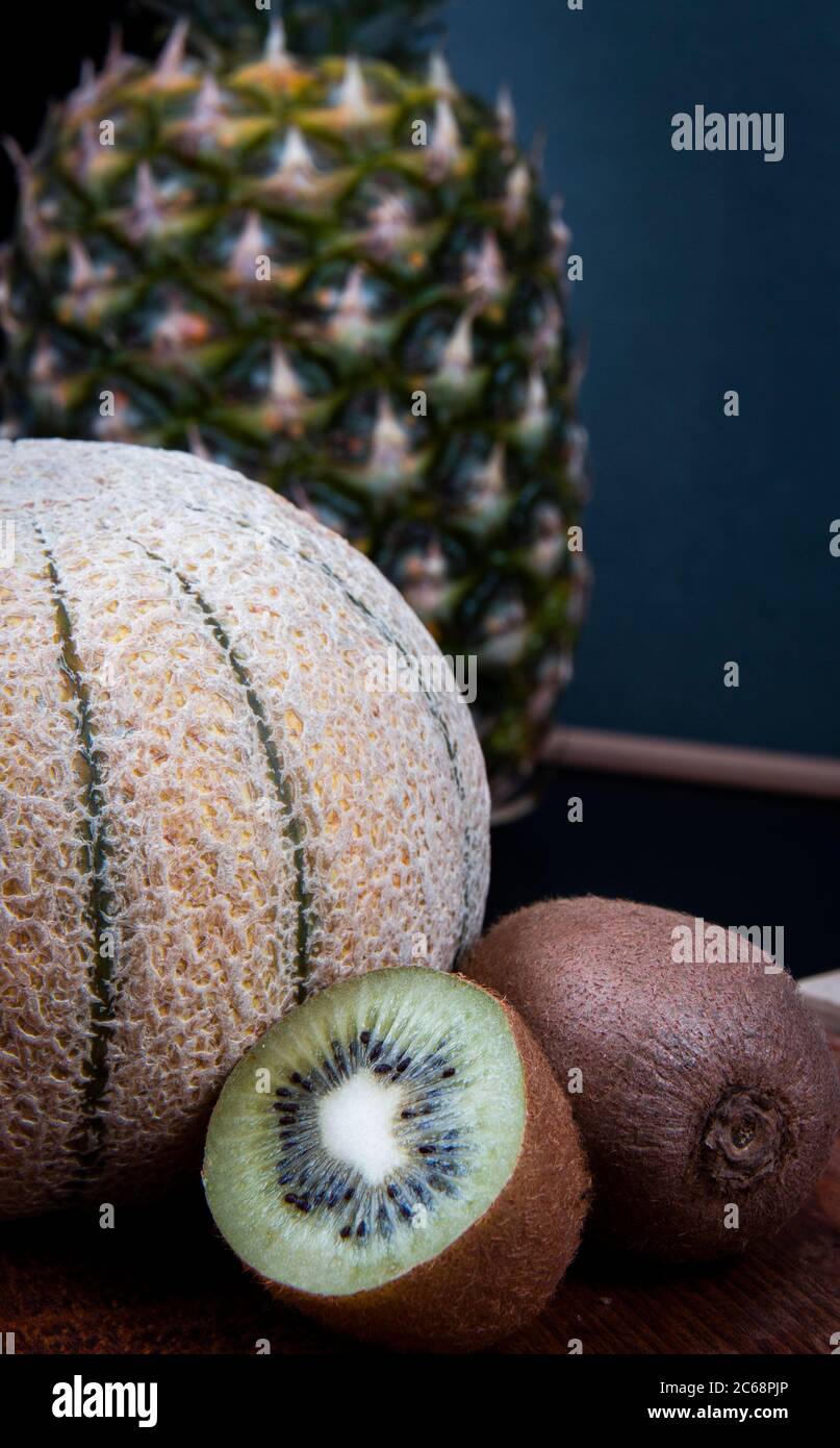 Un colpo vicino di alcuni frutti include un grande ananas, melone di miele e kiwis. Foto Stock