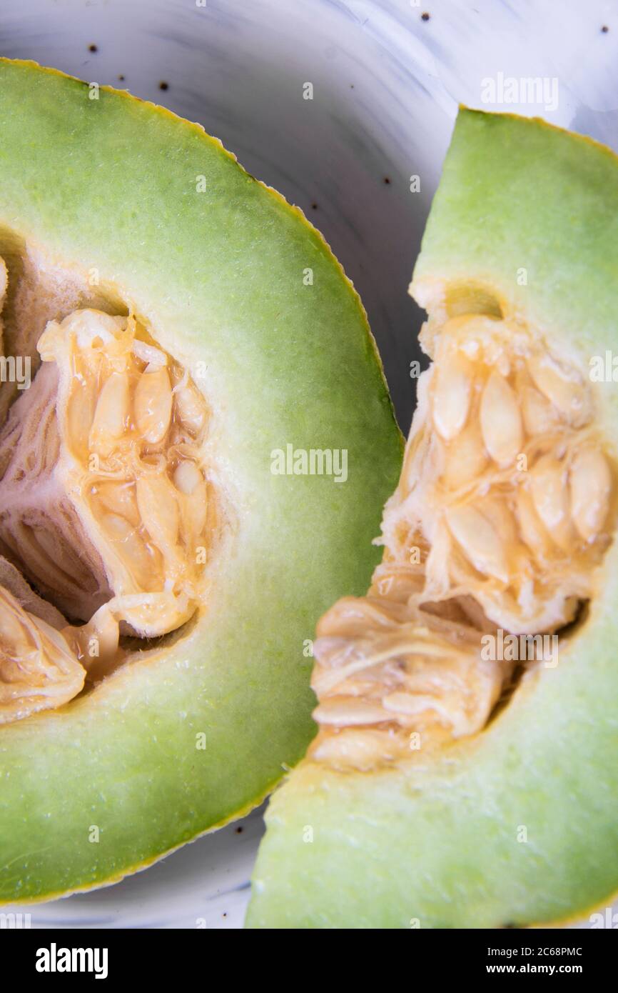 Metà di una rugiada in luna di miele vicino ad una fetta di melone verde tagliata fuori. Foto Stock