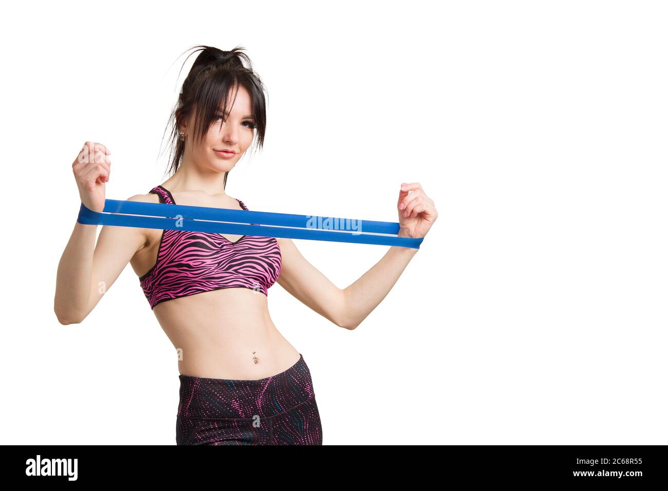 una giovane donna vestita per lo sport o il fitness con una pettinatura a coda di rondine, fa un esercizio con una fascia elastica con un espansore. Foto Stock