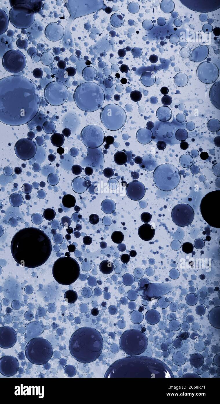 Bolle d'olio nell'acqua. I colori blu e nero sono misti. Foto Stock