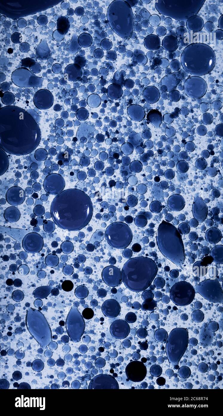 Bolle d'olio nell'acqua. I colori blu e nero sono misti. Foto Stock