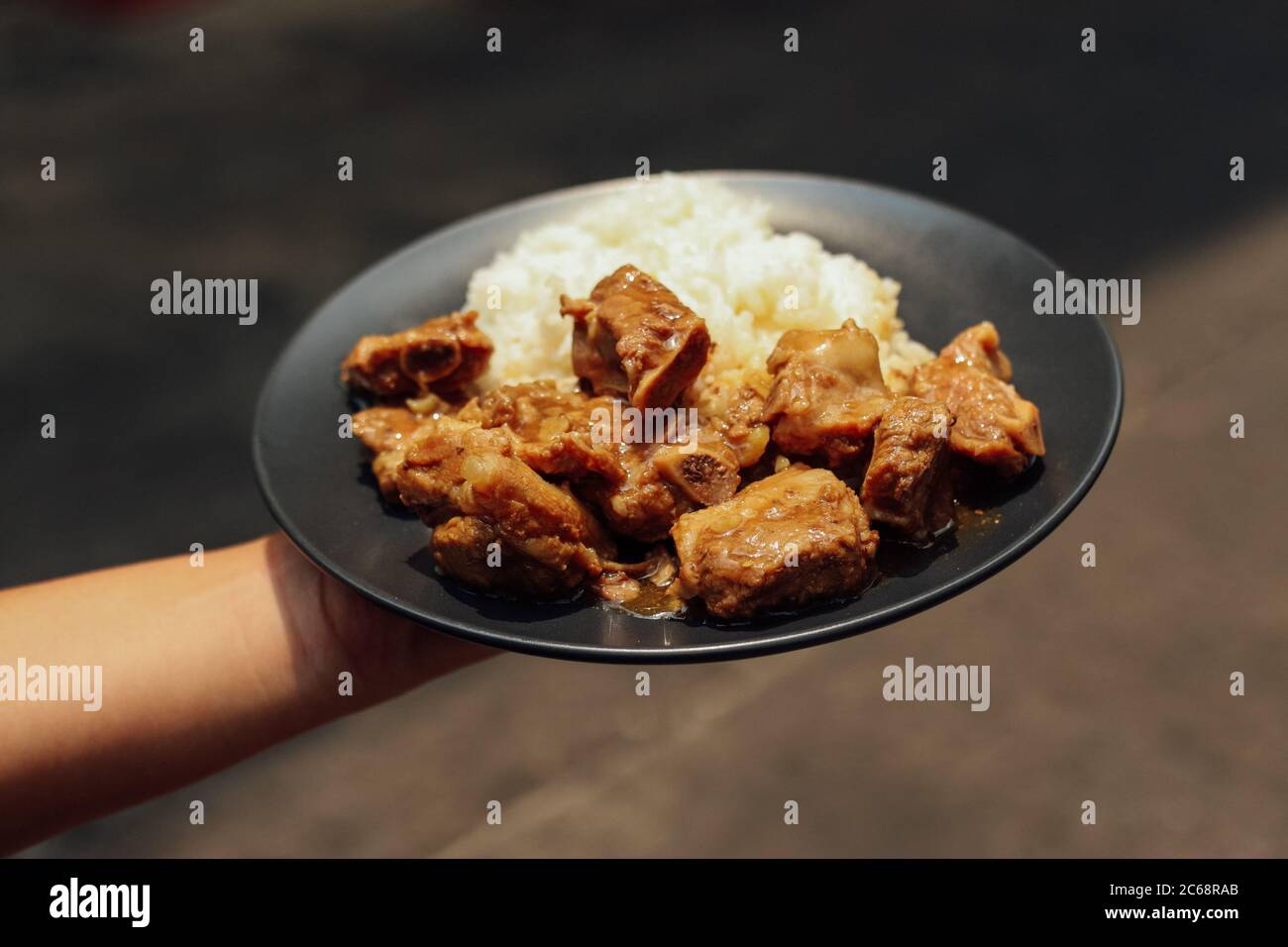 Salate ossa di maiale stufate con riso servite su piatto nero Foto Stock