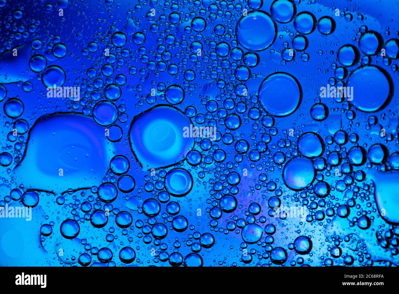 Bolle d'olio nell'acqua. Colori blu e nero. Foto Stock
