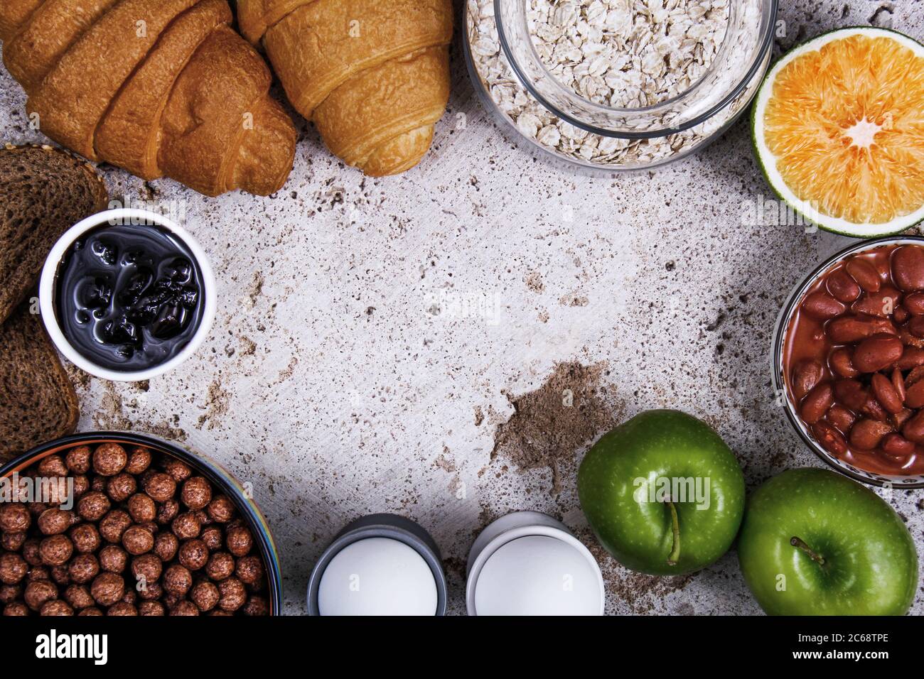 Un perfetto tavolo per la colazione pieno di frutta fresca: mela e arancia, diversi tipi di pane: Croissant e pane tostato, marmellata, bastoncini salati, avena e capretto Foto Stock