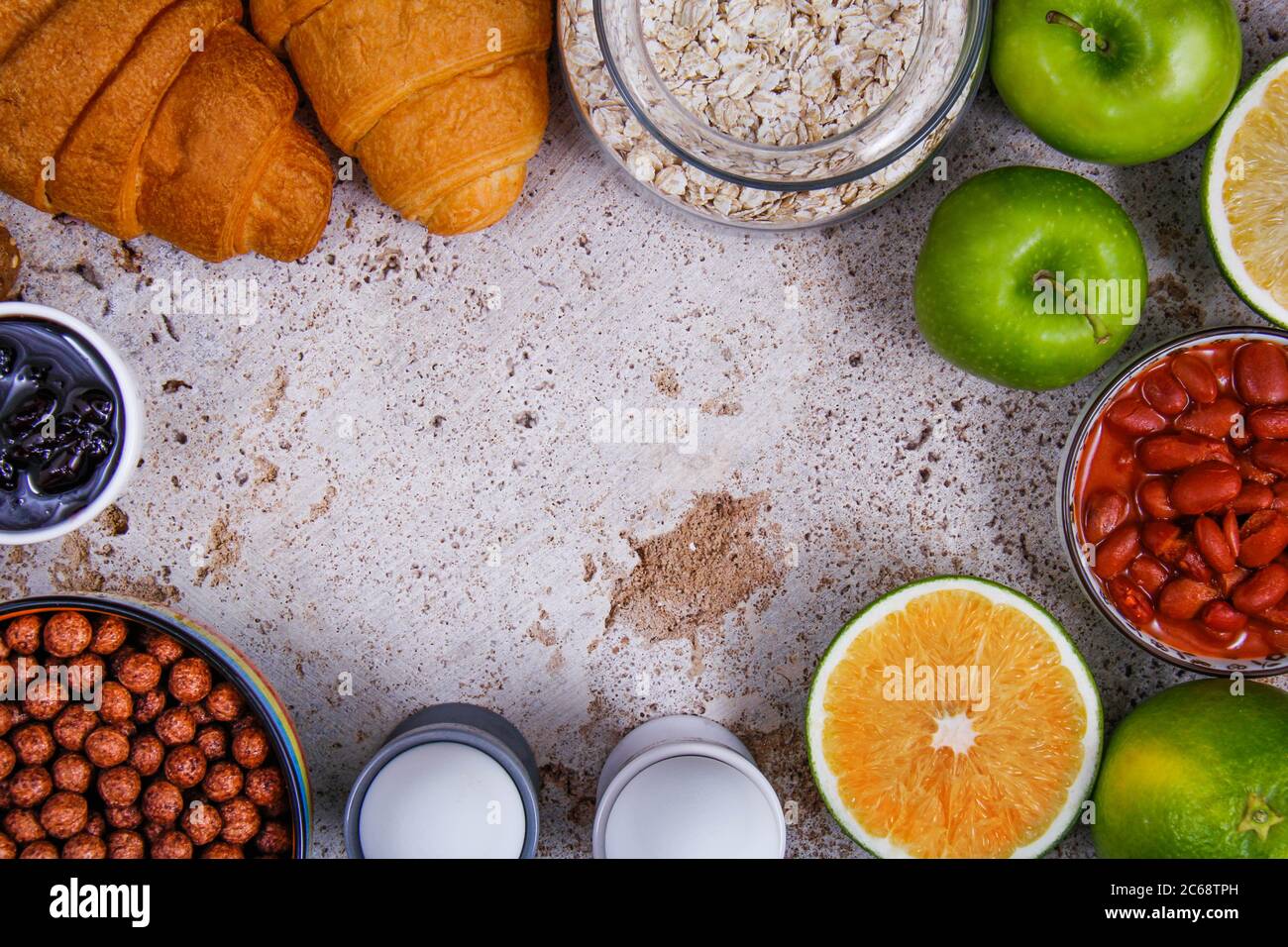 Un perfetto tavolo per la colazione pieno di frutta fresca: mela e arancia, diversi tipi di pane: Croissant e pane tostato, marmellata, bastoncini salati, avena e capretto Foto Stock