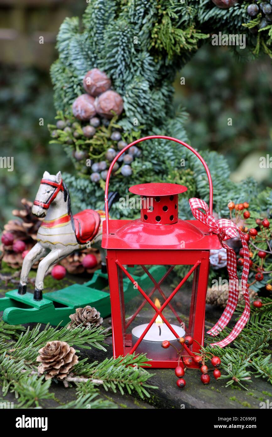 decorazione del giardino di natale con lanterna rossa, cavallo dondolo e corona dell'avvento Foto Stock