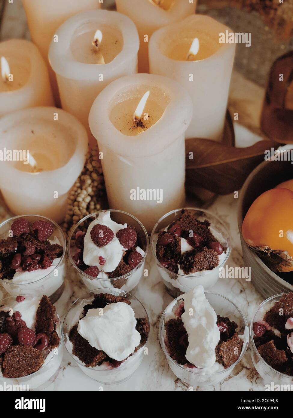 Dessert al lampone, biscotti e crema accanto alle candele Foto Stock