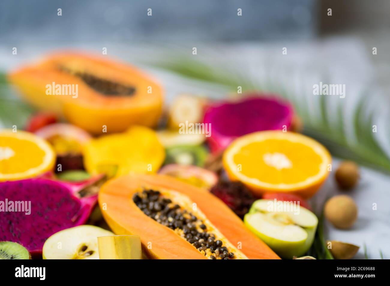 Set di frutta fresca esotica a fette. Assortiti maturi succosa estate tropicale frutta di stagione e foglie tropicali su tavola bianca. Messa a fuoco selettiva. Orizzontale Foto Stock