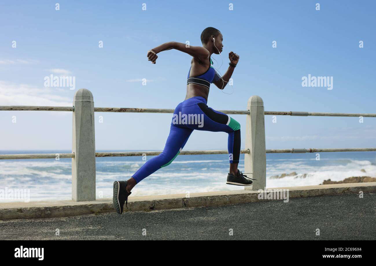 Un'intera foto di una donna corre sulla strada costiera. Fit atleta sprint femminile sul lungomare di mattina. Foto Stock