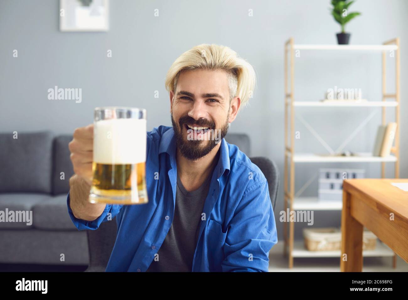 Ragazzo allegro con birra che parla con i suoi amici maschi online da casa. Bell'uomo che festeggia con gli amici sulla webcam Foto Stock