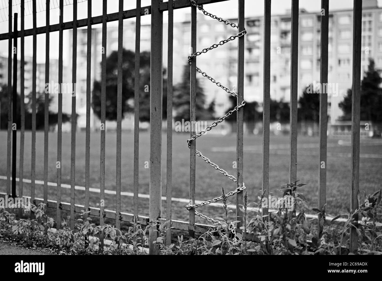 KOSICE, SLOVACCHIA, 4 AGOSTO 2019: Un divario nella copertura intorno allo stadio di calcio della scuola fissato da una catena di serpenti a croce-ciglia con costruzione appartamento sfocato Foto Stock