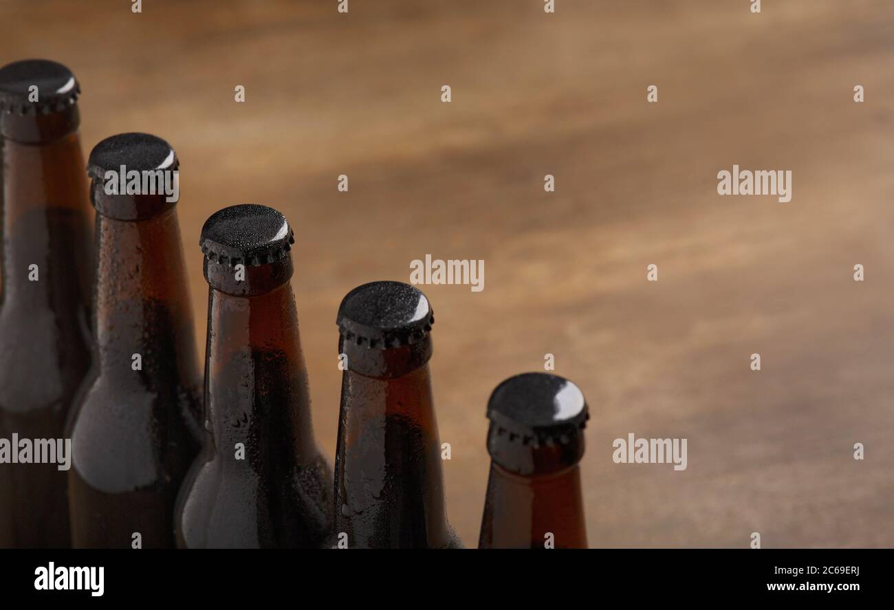 Industria della birra. Fila di bottiglie di birra scure con tappi su sfondo di legno Foto Stock